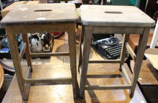 A pair of vintage laboratory stools with centre hand hold