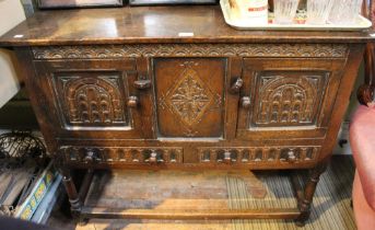 A 19th century oak sideboard with two carved doors over two drawers with carved centre panel