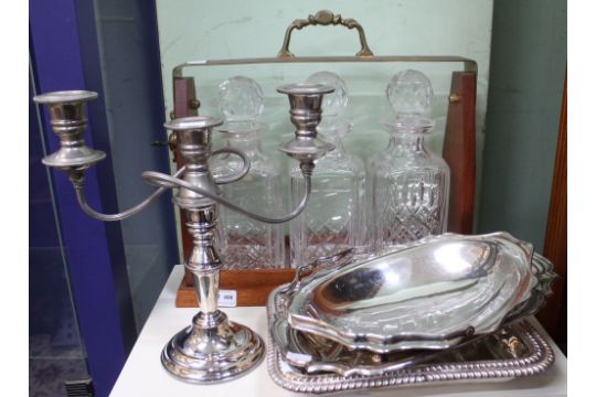 A three decanter tantalus, plated twin branch candelabra and various plated serving dishes