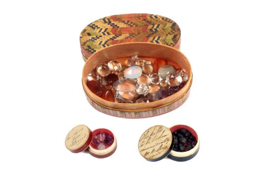 A collection of gem and paste stones contained in an oval split and coloured straw work box, circa