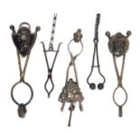 Five black finish mourning skirt lifters, comprising a scissor form example with shield form