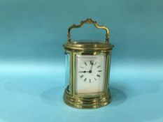 A brass carriage clock with oval case and strike action