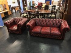 An oxblood Chesterfield three seater settee and a club armchair