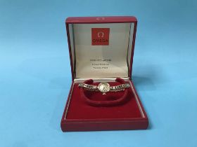 A gold ladies Omega wristwatch, with box and paperwork total weight 18 grams.