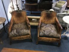 A pair of worn leather and brass studded armchairs