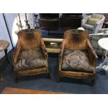 A pair of worn leather and brass studded armchairs