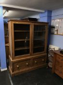 A pine two door glazed cabinet, on later stand with two drawers, W 143cm, D 49cm