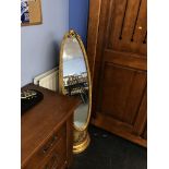 A gold coloured oval cheval mirror