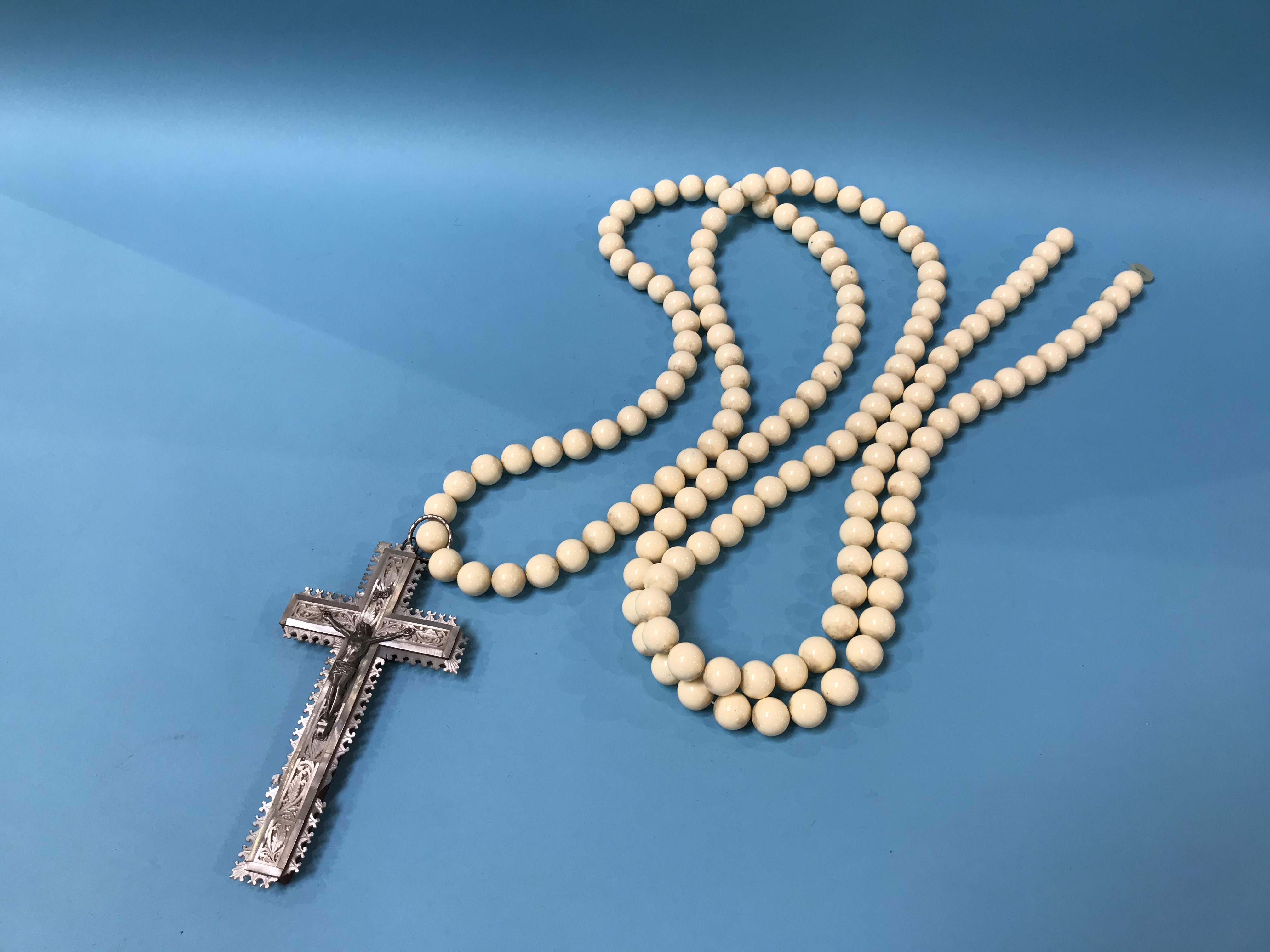 A carved mother of pearl crucifix and bead necklace