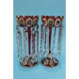 A pair of Victorian Bohemian style red lustres, each with enamelled decorative portraits, floral