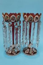 A pair of Victorian Bohemian style red lustres, each with enamelled decorative portraits, floral
