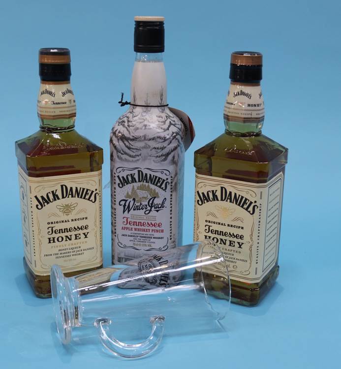 A Jack Daniel's glass, two bottles of Honey Jacks and one bottle of Winter Jack