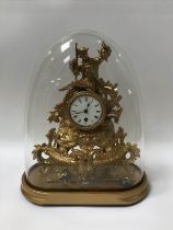 A Gilt metal clock, with enamelled lid, under a glass dome, H 36cm, W 28cm