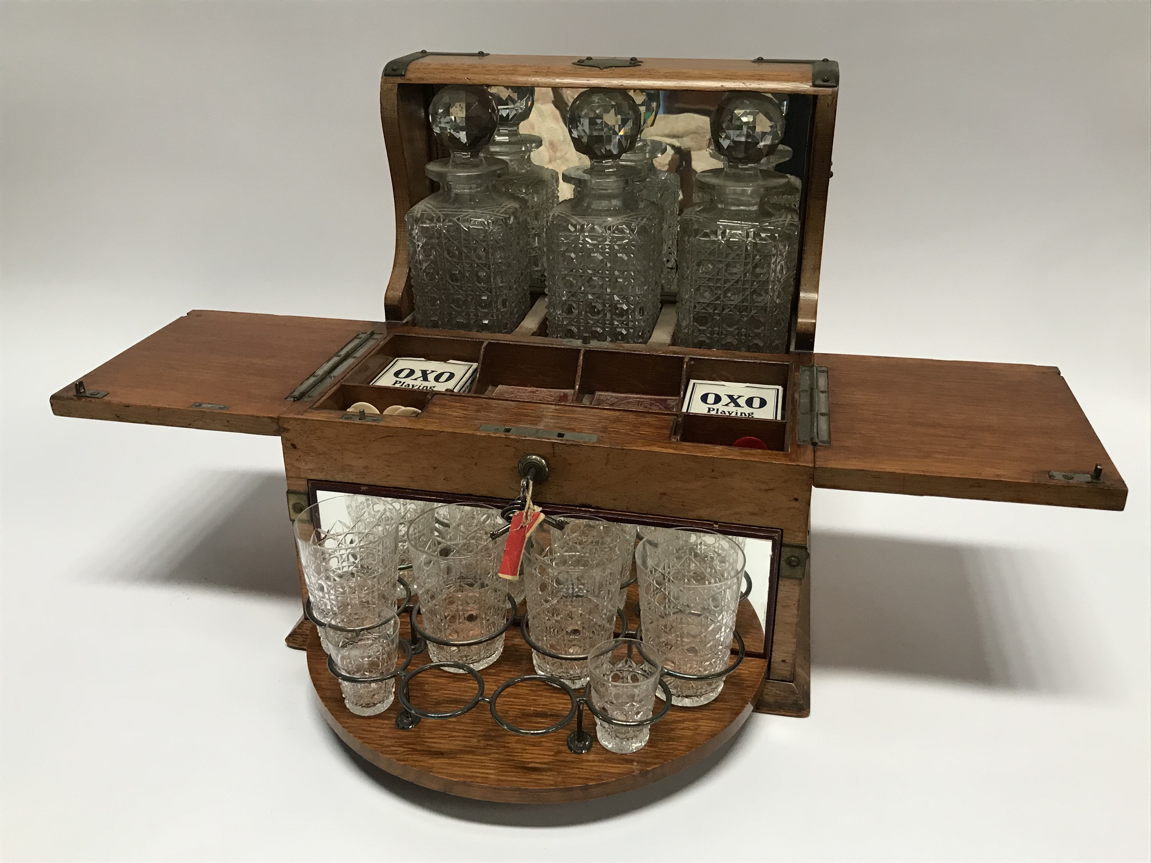 An oak tantalus and games compendium, with rotating glass holder