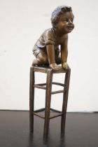 Bronze child on a chair signed
