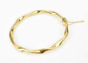 An Italian 18ct yellow gold bangle, of twisted form with safety chain, 6.5 cm inner width, weight 12