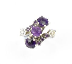 A white metal, diamond and amethyst dress ring, set with three central round cut amethyst flanked by