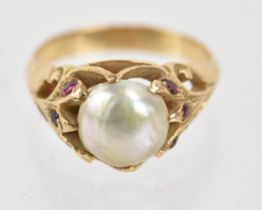 A pearl and ruby yellow metal ring, the central pearl in a claw shaped, the pierced and scroll