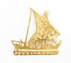 A yellow metal brooch modelled as a sailing boat, with etched floral detail to the mainsail, with