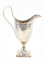 A George III silver milk jug by George Burrows, London 1788, of helmet shape with engraved and