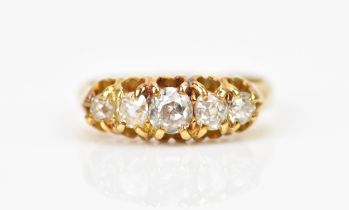 A yellow metal and five stone diamond ring, set with graduated old mine cut diamonds, the central