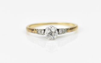 An Edwardian yellow metal and diamond solitaire ring, the central old cut stone flanked with two