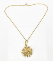 An Edwardian yellow metal, diamond and seed pearl starburst pendant on a 9ct gold chain, the pendant