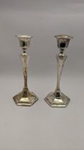 A pair of candle sticks hallmarked Birmingham 1946 having a tabled stem on a hexagonal base