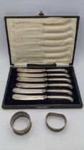 Two silver napkin rings 29.5g together with a cased set of six silver handled butter knives