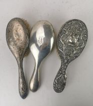 Three dressing table hair brushes to include silver brushes and a white metal embossed hair brush