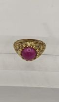 A gold coloured ring set with a pink cabochon, 8.8g Location: