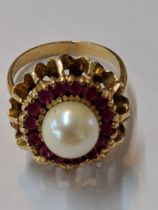 A yellow metal pearl ring surrounded by red coloured stones, tested as 14ct, 5.9g Location:
