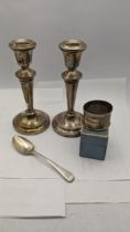 Mixed silver to include a pair of weighted candle sticks a silver napkin ring and tea spoon