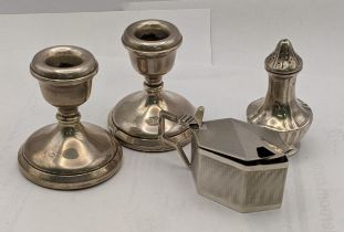 A pair of silver dwarf candlesticks weighted, a pepper pot and a mustard with blue glass liner