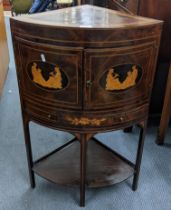 An Edwardian mahogany corner table having a bow front and the doors with marquetry inlaid with