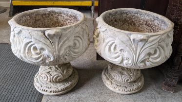 A pair of reconstituted stoneware garden planters having moulded floral decoration and raised on