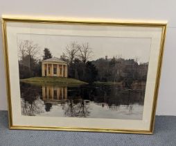 A framed and glazed print depicting a lake scene, with a pillared building to the background