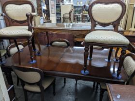 A reproduction mahogany extending dining table on turned and fluted tapering legs and casters,