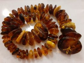 A string of 68 vintage amber disc shaped beads of irregular form and varying colours to include
