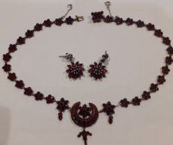 An early 20th Century white metal and garnet coloured stone necklace having crescent moon and floral