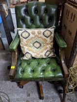 A mahogany framed and green leather upholstered button back swivel armchair, with loose cushion