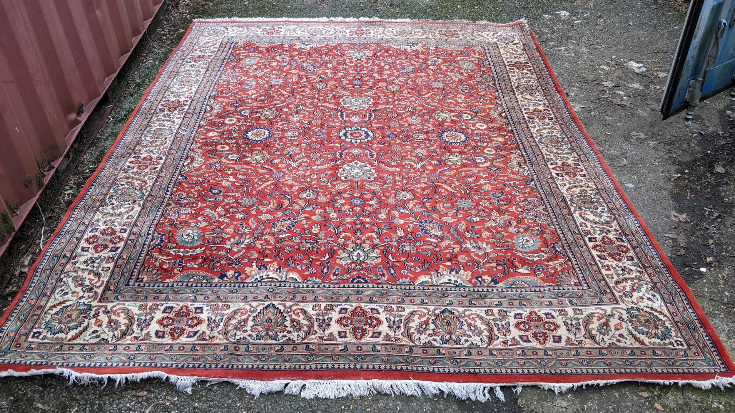 Persian hand woven rug having a red ground with a floral design multiguard borders and tasselled