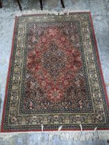 A Super Kashan handwoven Persian style rug with floral decoration on a red, blue and green ground,