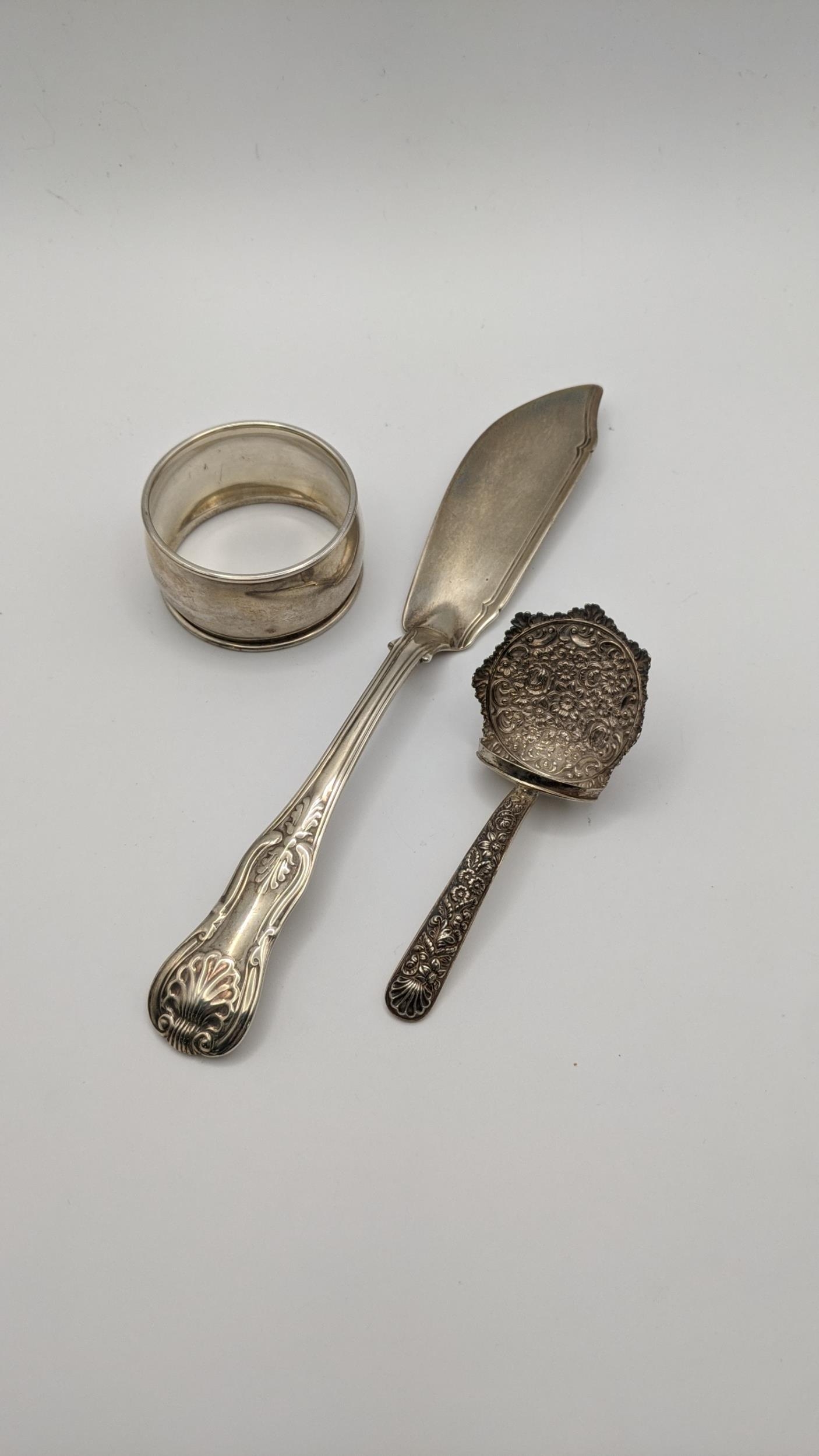A silver fish knife along with a silver napkin ring and a silver embossed caddy spoon, 78.2g