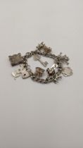 A silver charm bracelet having silver charms to include the Holy Bible, a hedgehog, and others 55.8g