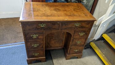 A 19th century walnut veneered kneehole desk having six drawers and a central cupboard door on