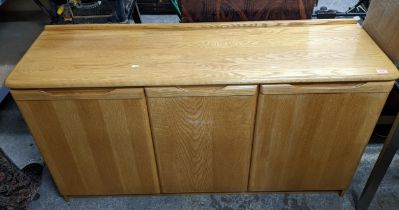 A modern light wood sideboard with extended back, central pull-out cutlery tray above two other