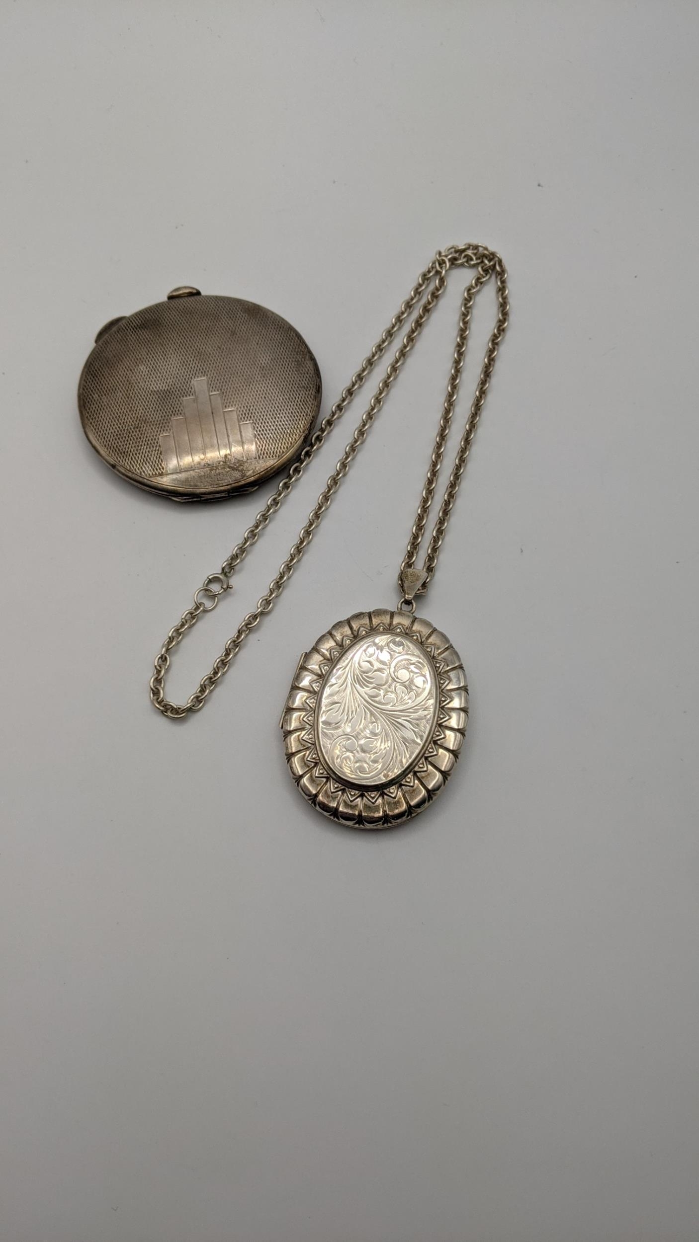 A silver locket having embossed and engraved detail on a silver necklace together with a silver
