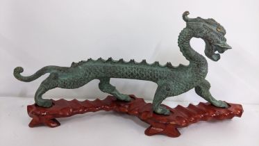 A modern Chinese bronze ornament of a dragon, raised on a treen base Location: