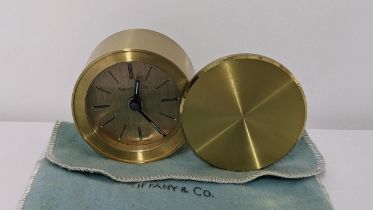 A Tiffany & Co travel alarm clock in a lacquered brass case with rotating cover, numbered 200570